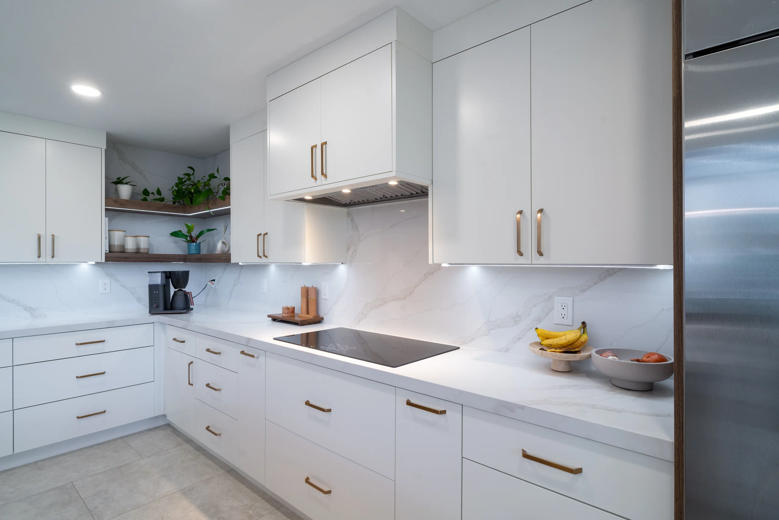 White flat-panel kitchen cabinets with brass hardware